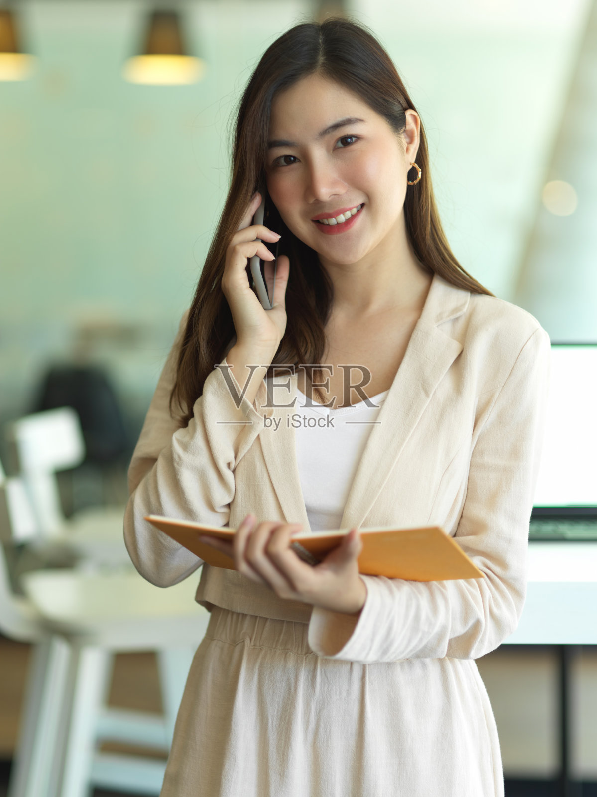 女商人拿着日程表,站在办公室里打电话照片摄影图片