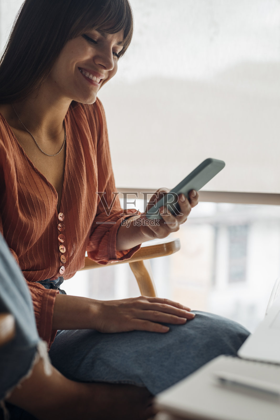 在家工作时使用手机的快乐美丽的年轻女人照片摄影图片