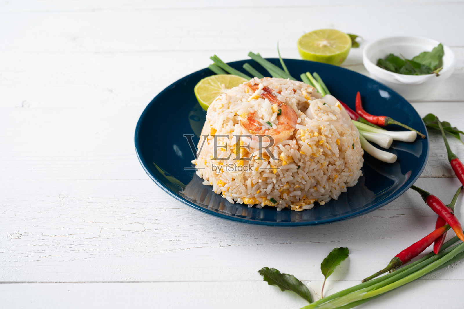 木桌上的蓝色盘子上的虾仁鱿鱼炒饭照片摄影图片