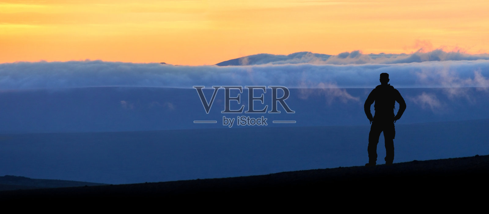 徒步旅行者站在壮观的蓝色分层山脉剪影。冰岛的日落景观。照片摄影图片