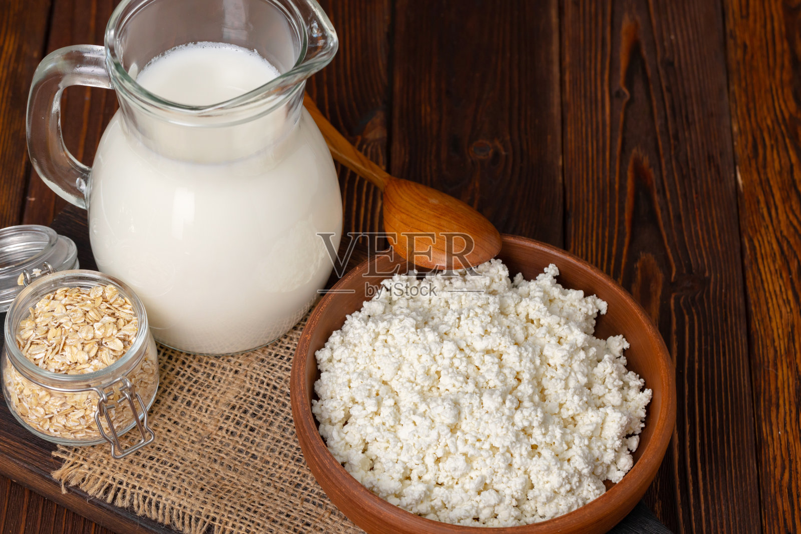 木桌上放着一大罐牛奶和一碗白干酪照片摄影图片