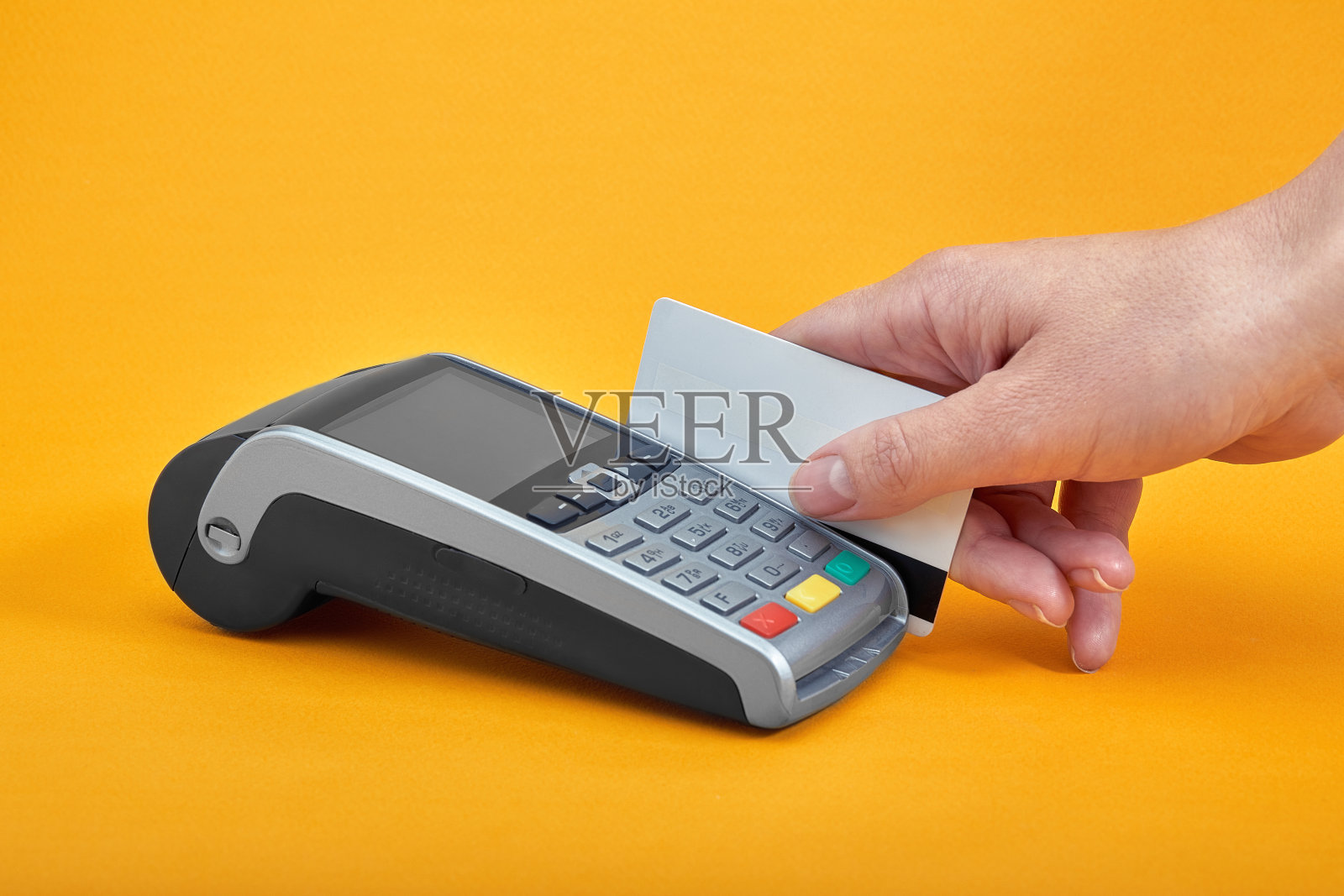 黄色背景上的缴费按钮,旁边是拿着塑胶卡的人手照片摄影图片