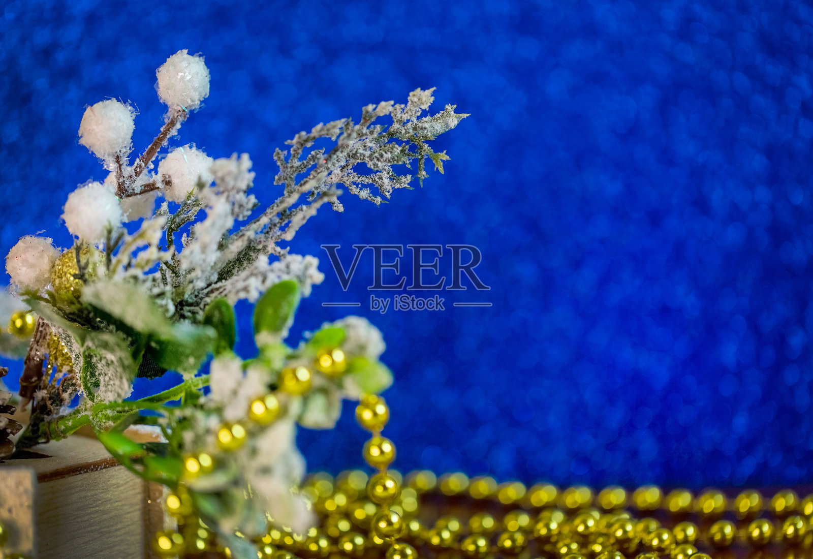 一根雪中的树枝,一颗松果和蓝色背景上的金珠子。圣诞节,2021年新年。副本的空间。有选择性的重点。照片摄影图片