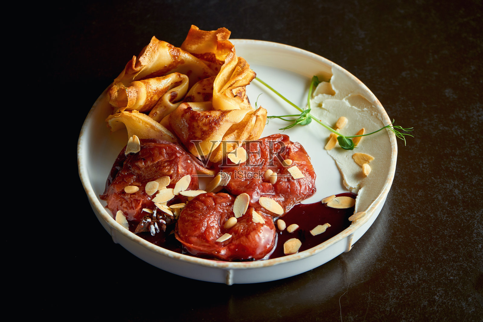 油炸可丽饼配烤李子和杏仁。早餐吃甜食。有选择性的重点照片摄影图片