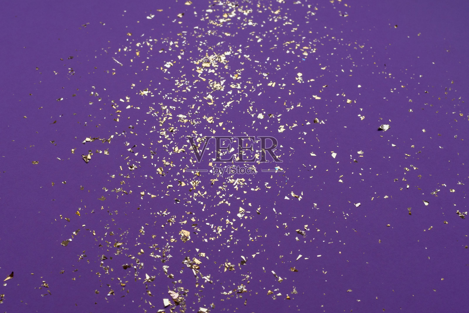 紫色背景上闪耀着金色的五彩纸屑。俯视图,复制空间照片摄影图片