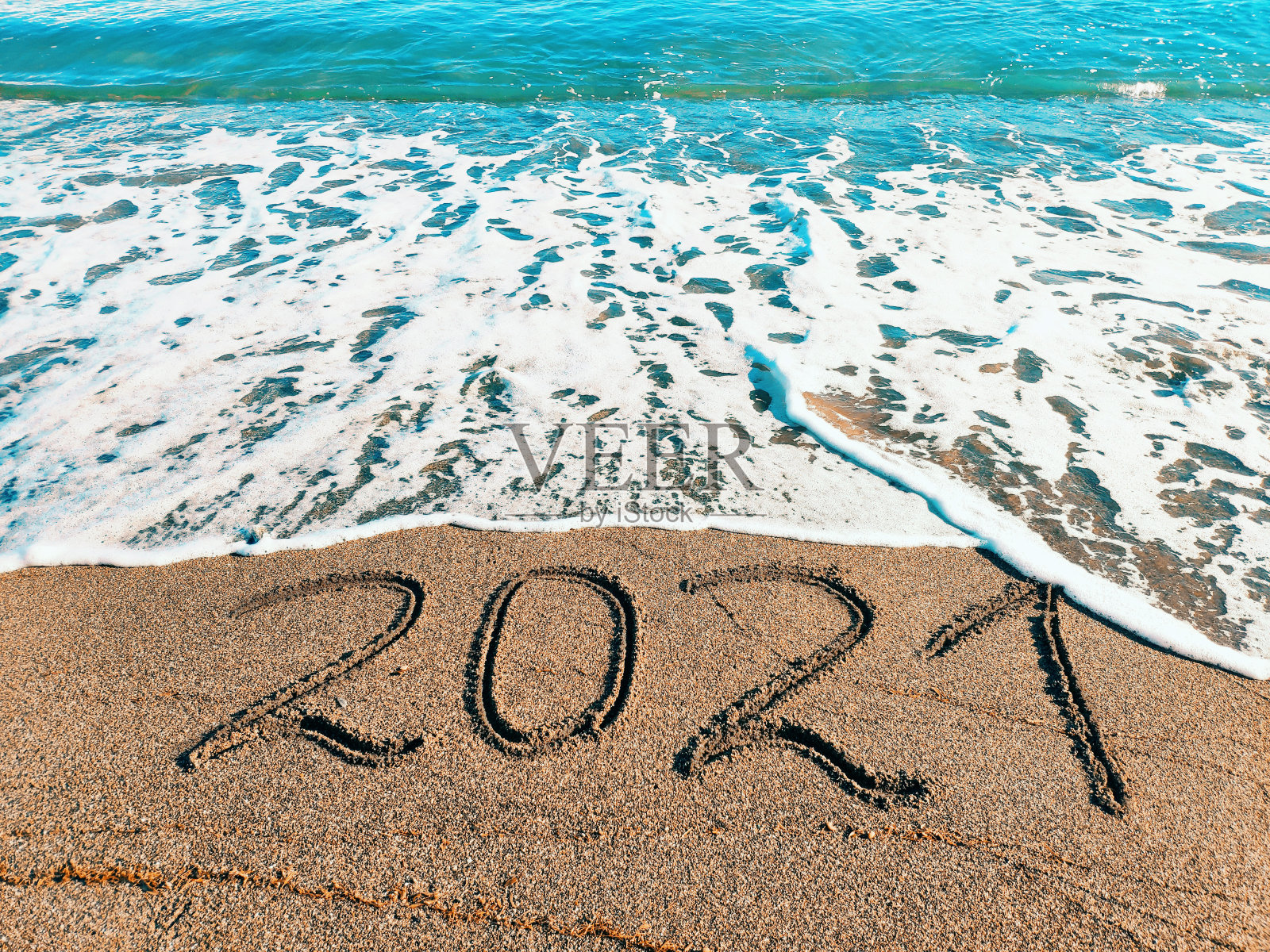 在一个美丽海滩的沙滩上写着2021年。新年快乐的概念。照片摄影图片