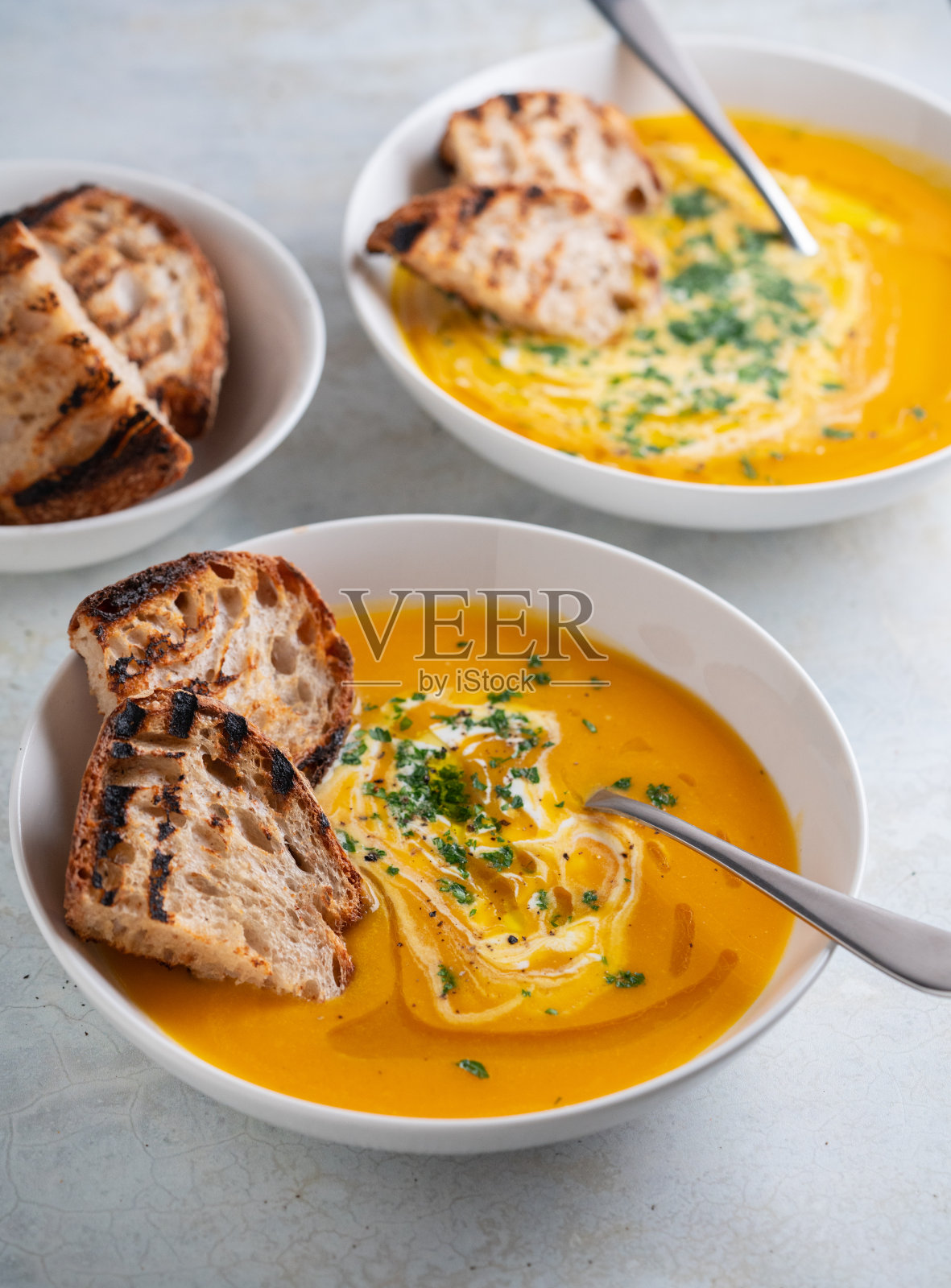 南瓜汤装在碗里,配上面包丁、欧芹和橄榄油。照片摄影图片