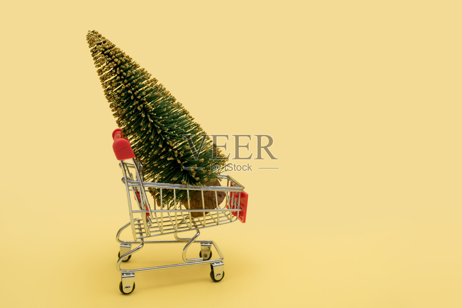 超市手推车上的绿色圣诞树。在商店里买卖的概念。照片摄影图片