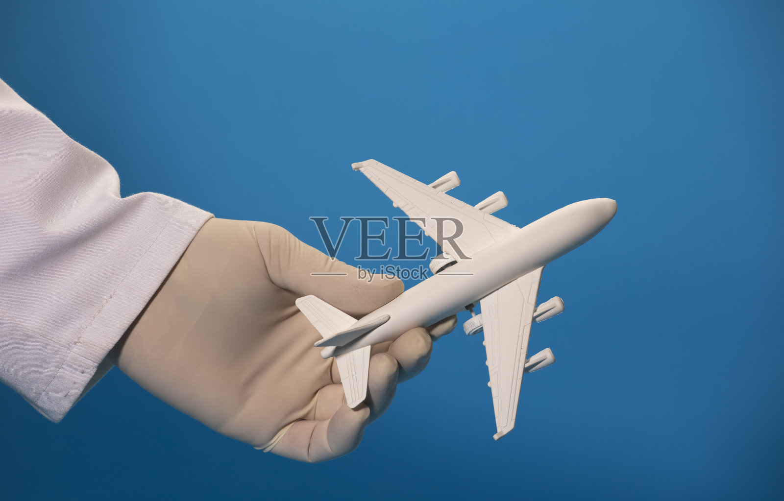白色飞机医生的手,带手术手套和蓝色背景照片摄影图片