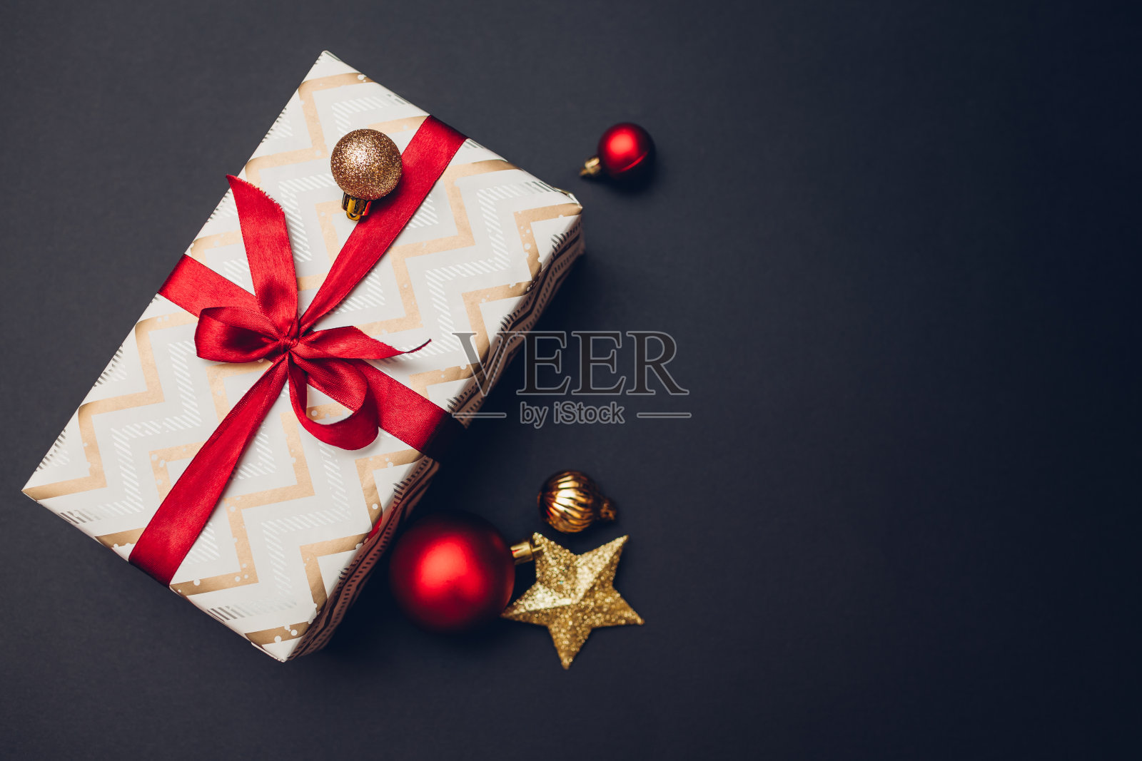 圣诞及新年礼盒,以节日纸包装,以红色丝带及黑色蝴蝶结装饰。照片摄影图片