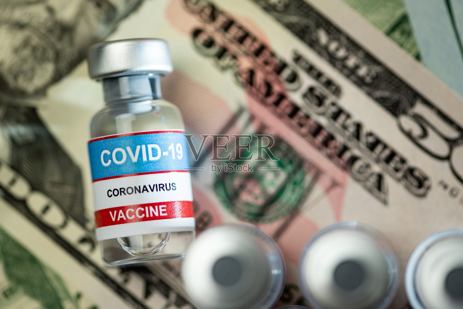关闭小瓶超过一堆美元- Covid-19疫苗接种的概念照片摄影图片