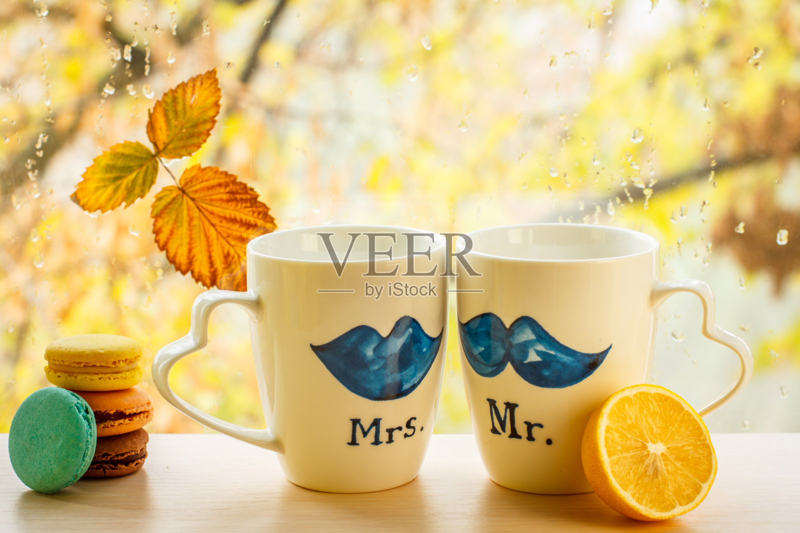 杏仁饼干,杯子上的柠檬和秋天的黄叶玻璃上模糊的背景与水珠。照片摄影图片