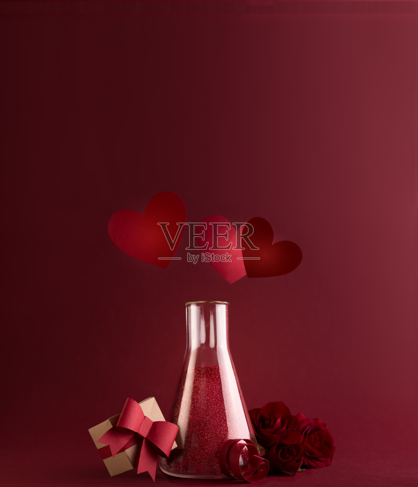 爱情化学,情人节快乐卡片在实验室玻璃烧瓶里闪闪发光的药水和上面的红心。照片摄影图片