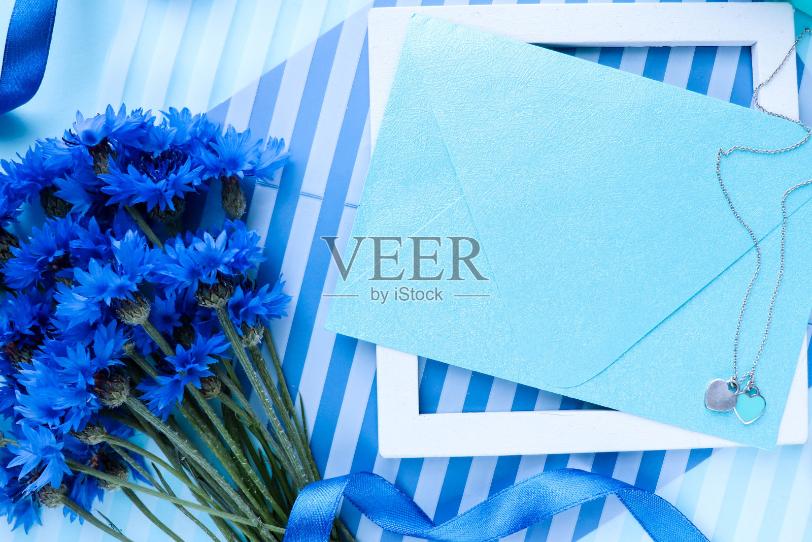 一束白色背景的蓝色矢车菊和一个信封照片摄影图片