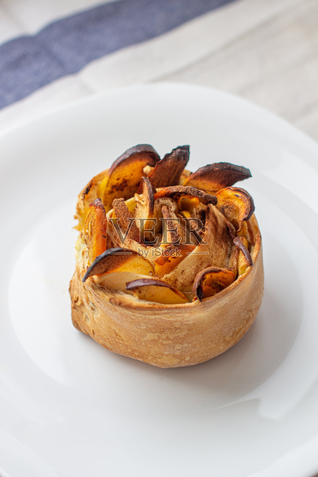 白色盘子上放着手工制作的肉桂和苹果面包。照片摄影图片