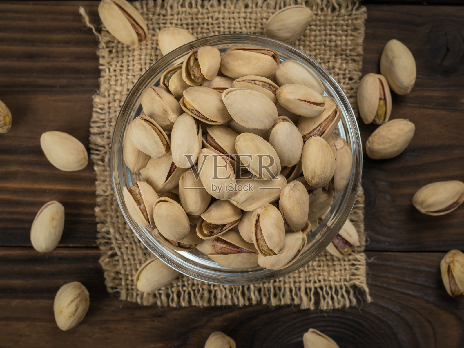 用粗麻布裹着开心果的玻璃碗。照片摄影图片