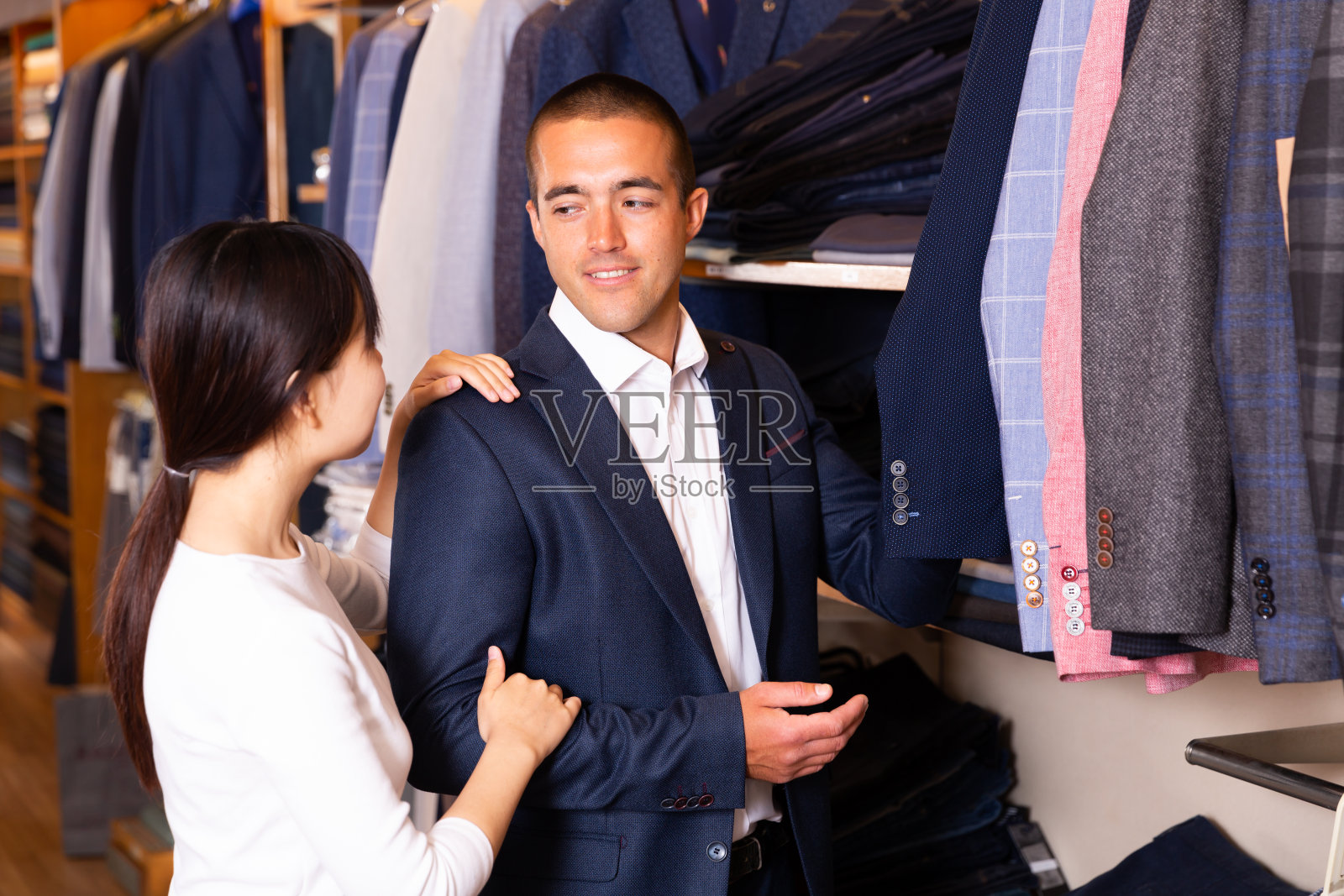 中国女售货员在商店帮助顾客选择衣服照片摄影图片