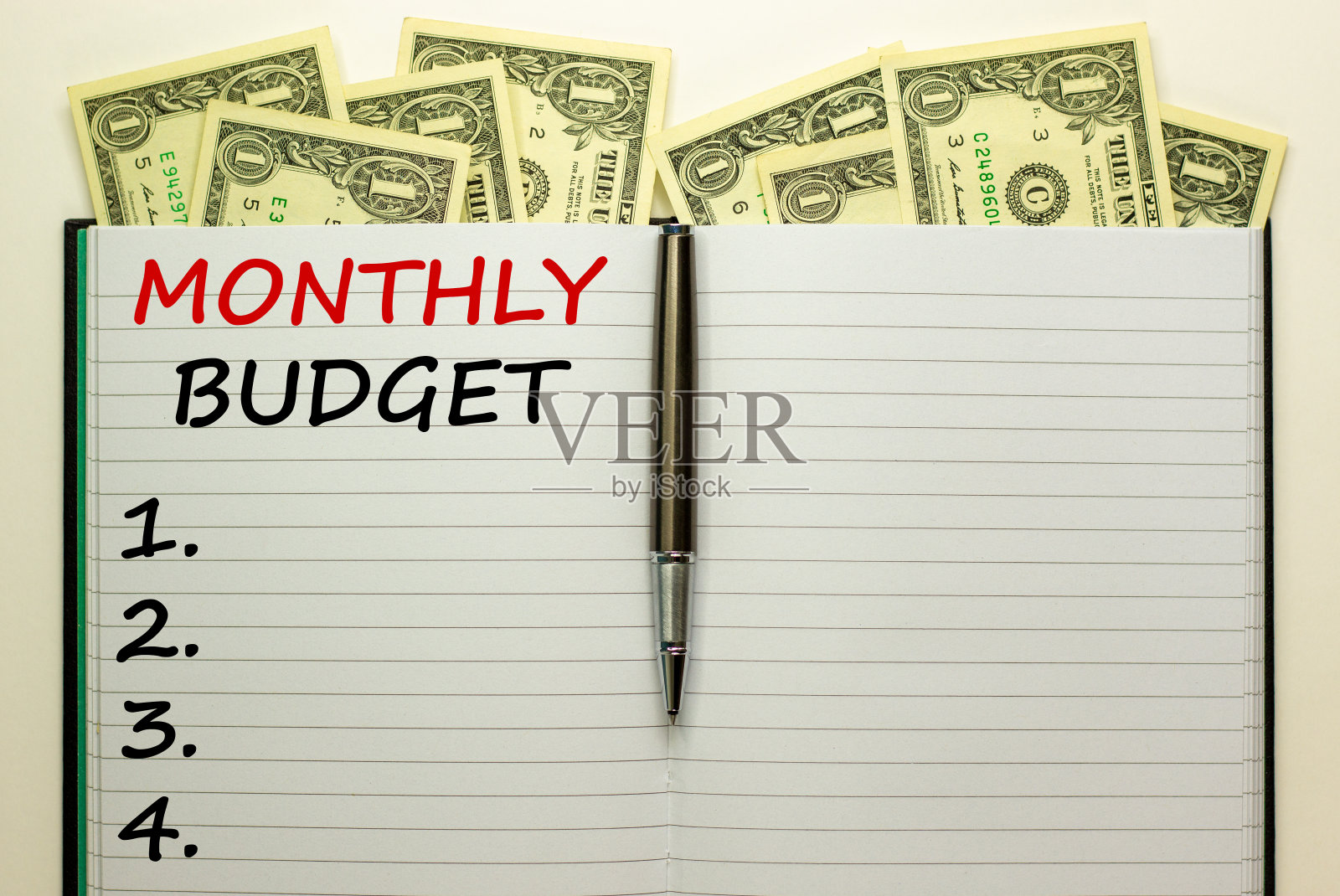 白色便条上刻有“每月预算”在美丽的白色背景,金属笔,美元。经营理念,复制空间。照片摄影图片