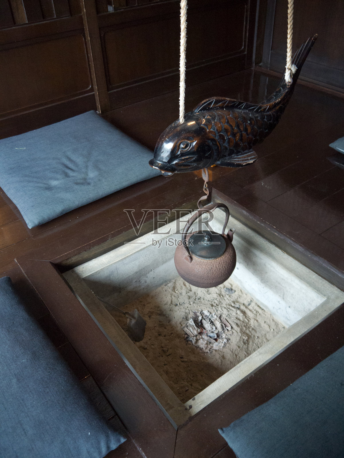 拉帕尼斯人的房子内部有irori壁炉,雕刻的木制锦鲤鱼和铸铁水壶在发光的煤炭照片摄影图片