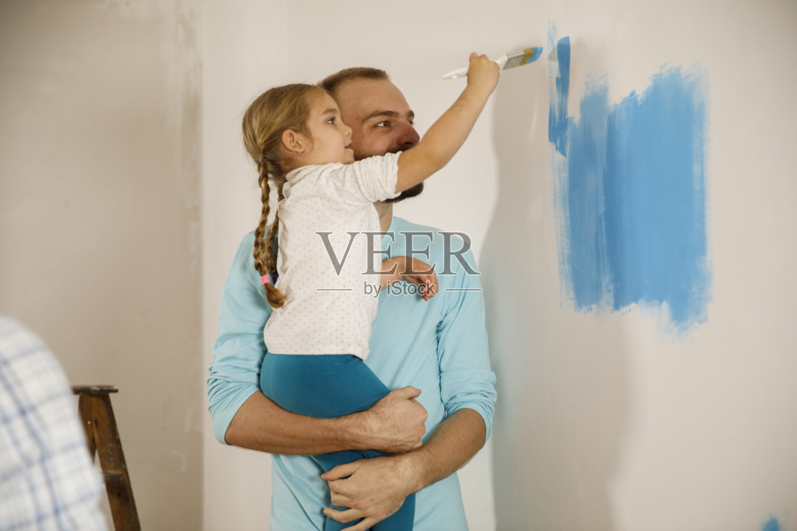 爸爸和他可爱的小女儿把墙涂成了蓝色照片摄影图片