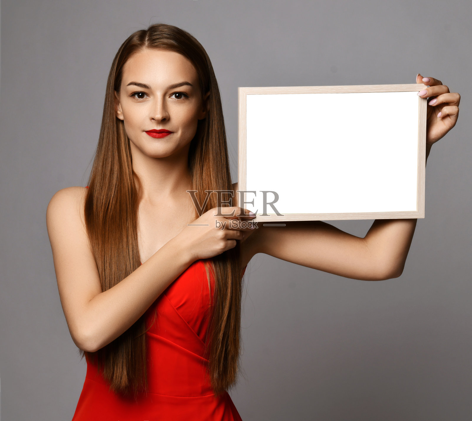 年轻的微笑漂亮的女人在红色连衣裙与长丝绸直发持有白色的黑色文本和字母模型在手中照片摄影图片