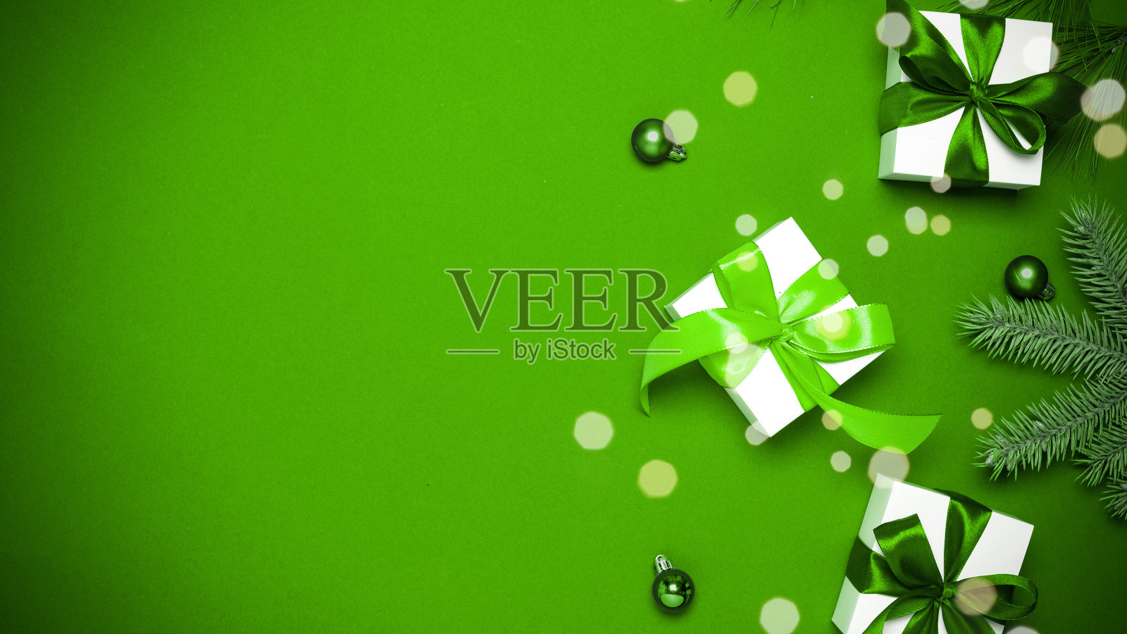 节日圣诞节的背景。白色礼物与祖母绿蝴蝶结,绿色球和闪闪发光的灯在圣诞装饰在绿色背景的贺卡。冬季节日构图用拷贝空间。照片摄影图片