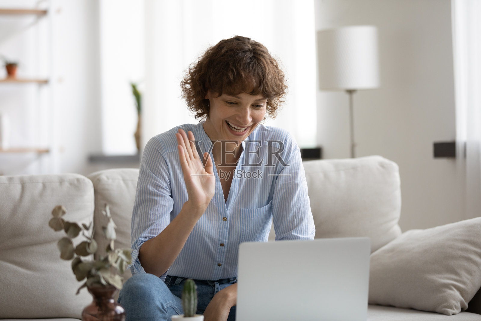近距离观看微笑的女人挥手,在家里使用笔记本电脑照片摄影图片