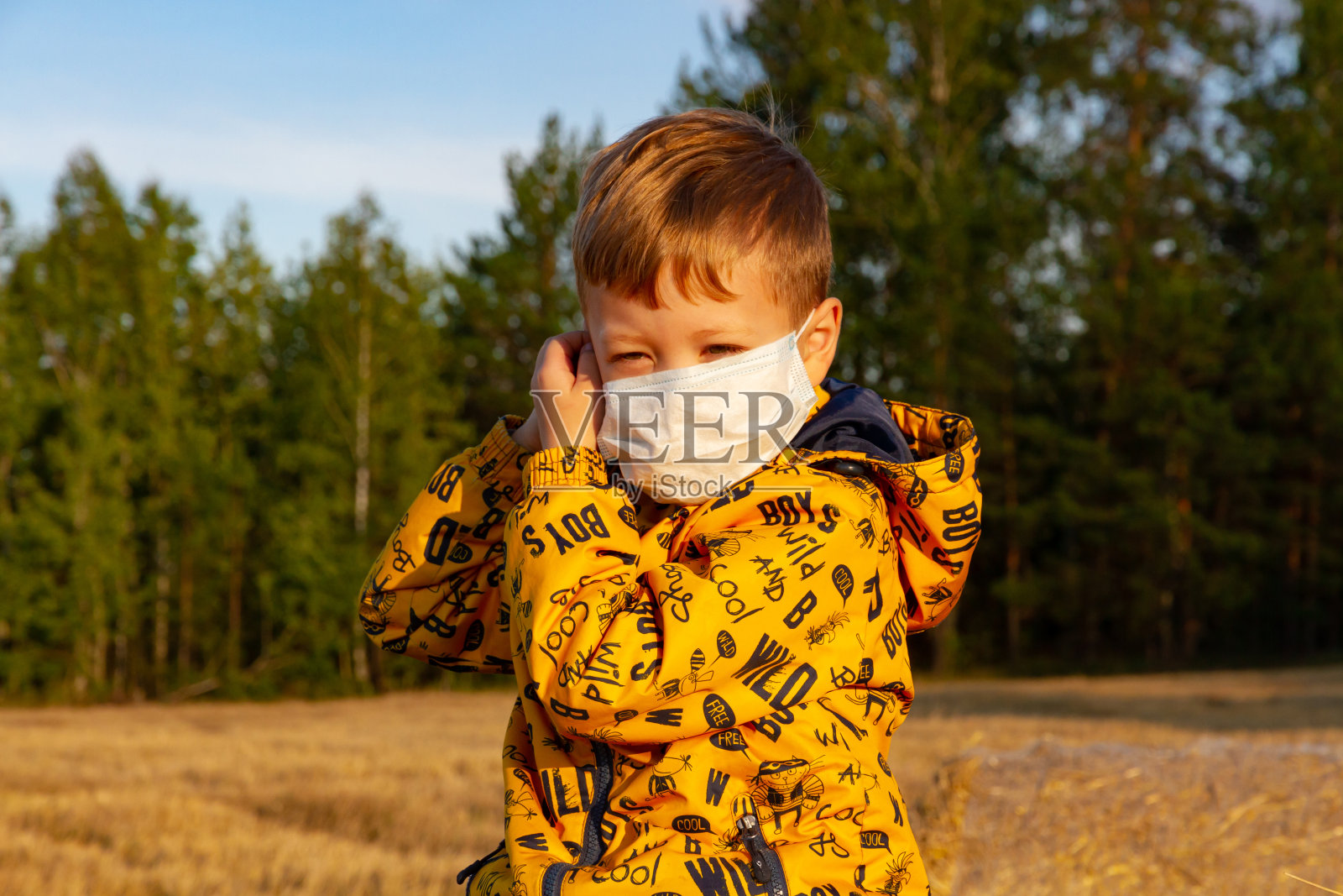 一个阳光明媚的日子,一个男孩戴上医用口罩照片摄影图片
