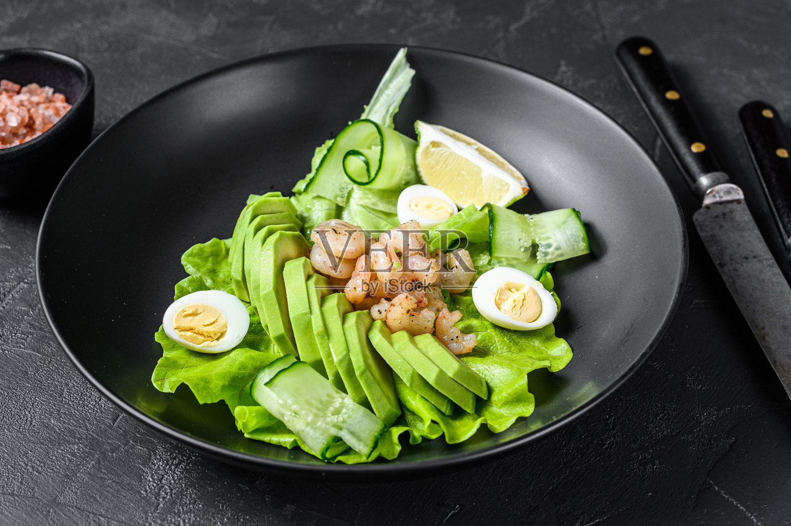 新鲜海鲜沙拉配烤虾、鸡蛋、牛油果和黄瓜。黑色背景。俯视图照片摄影图片