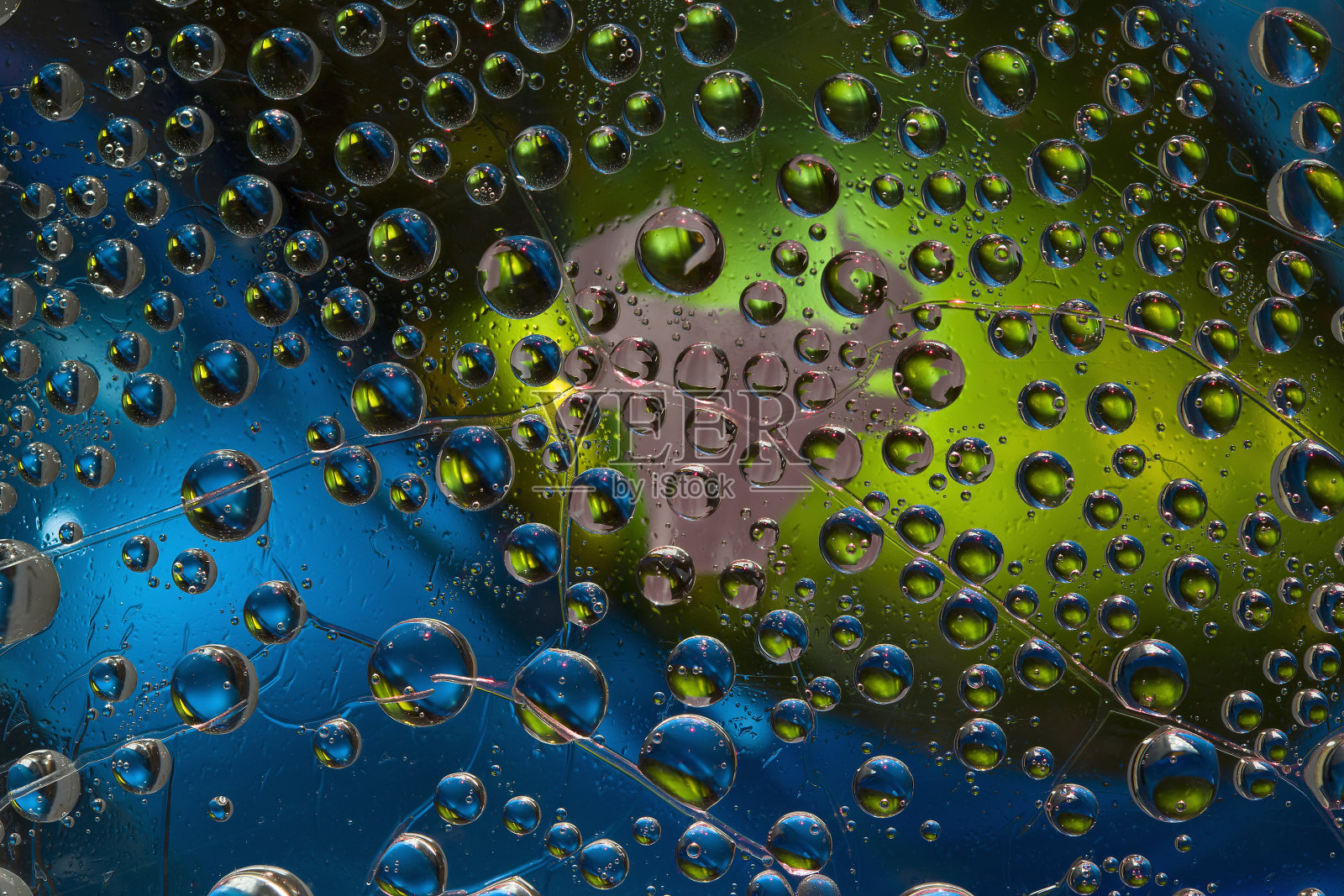 多色的水滴位于蓝绿色的镜子背景和一个棕色的公牛剪影。照片摄影图片