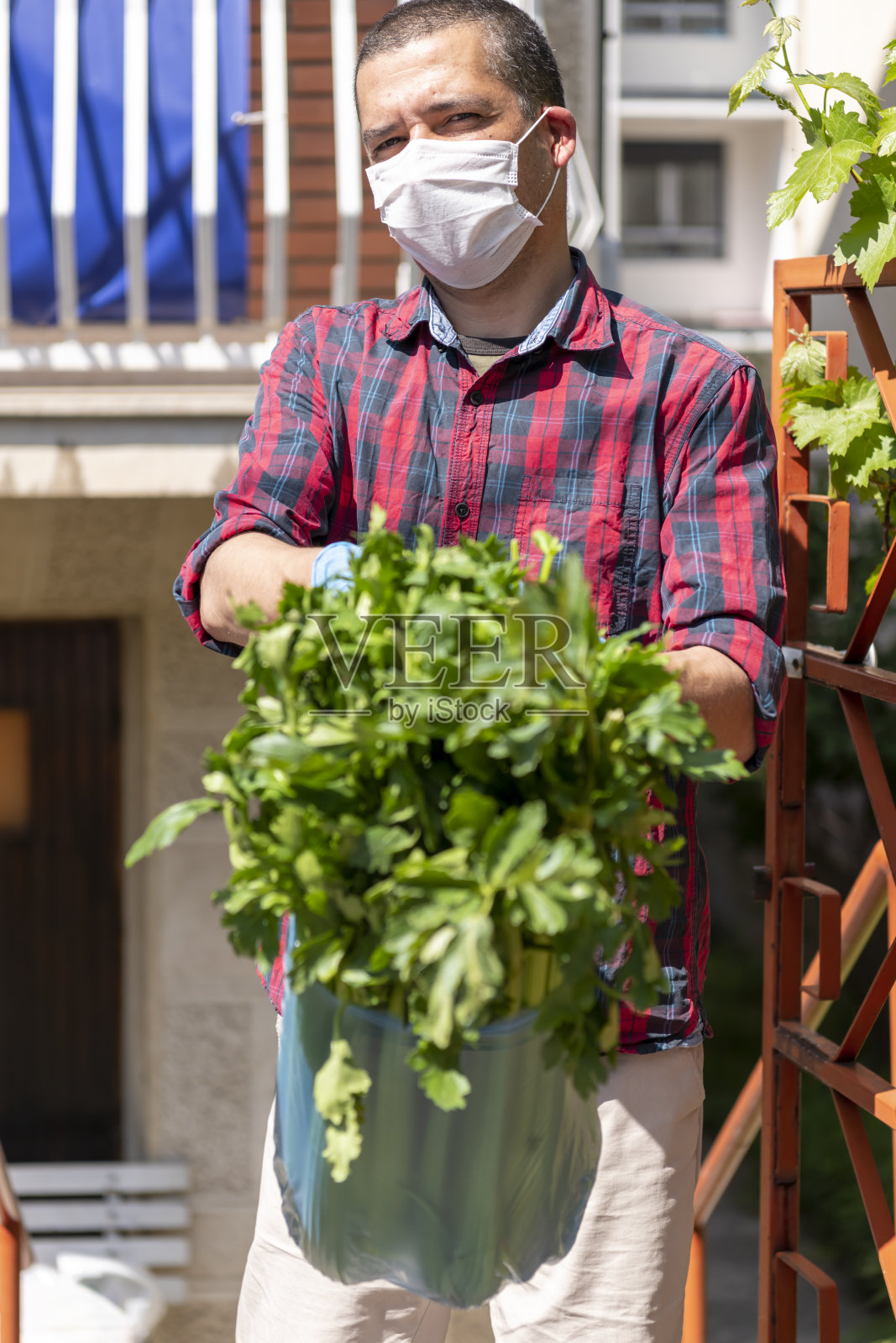 在疫情期间,一个成熟的男人正在给一个被隔离的人送食物。照片摄影图片