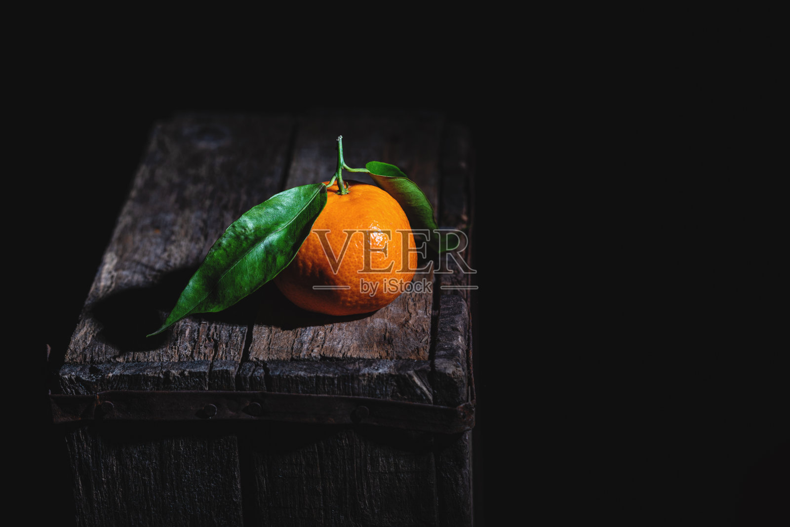 橘子和叶子在一个旧木箱上。低调的摄影。照片摄影图片