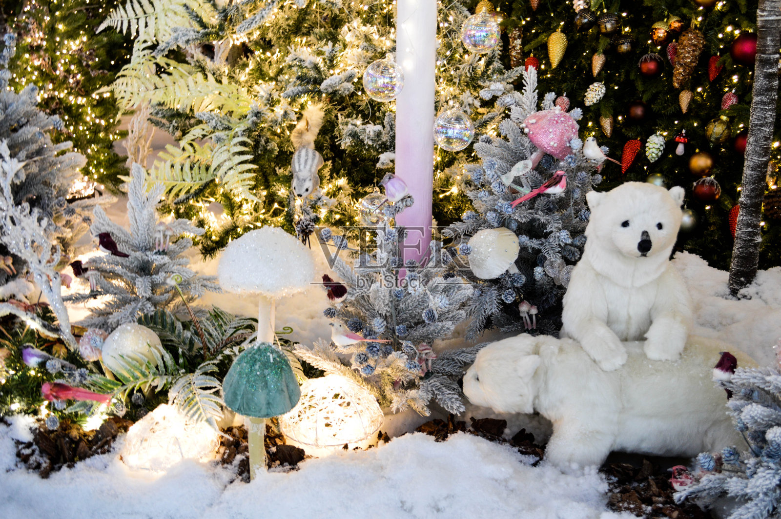 商店橱窗装饰,购物中心装饰。带花环的人造白云杉。他们旁边是两只北极熊幼崽。森林里的人造牛肝菌照片摄影图片