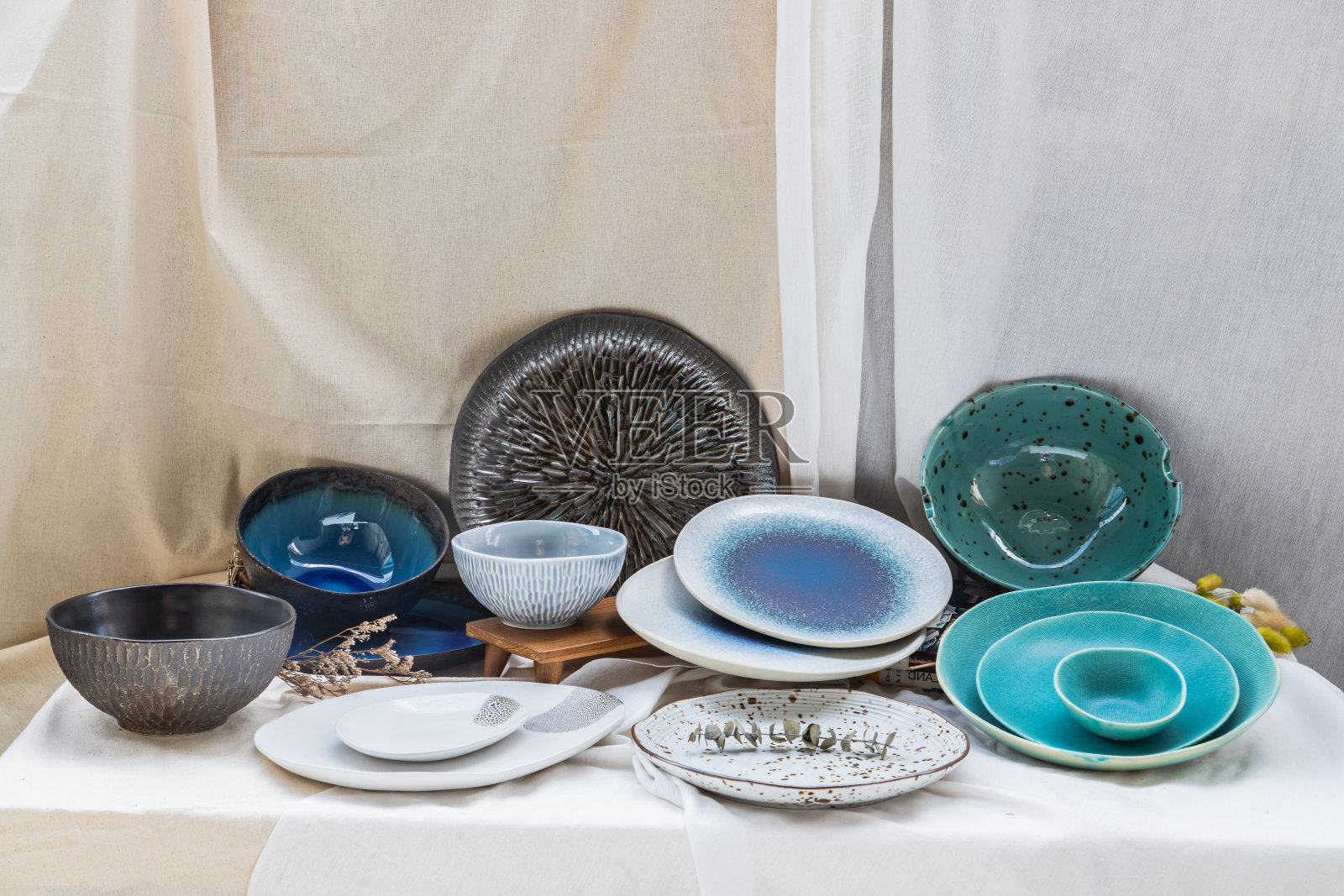不同的陶瓷板和碗在印花布的背景。照片摄影图片