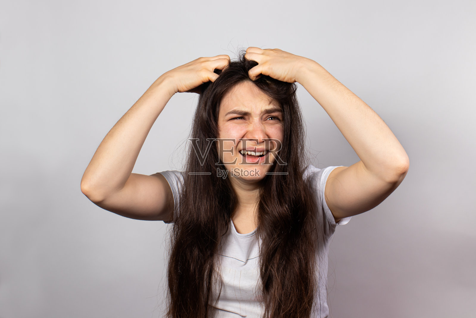 女孩用双手挠着头,头皮发痒,因为有传染性的虱子。在人类生虱子。照片摄影图片