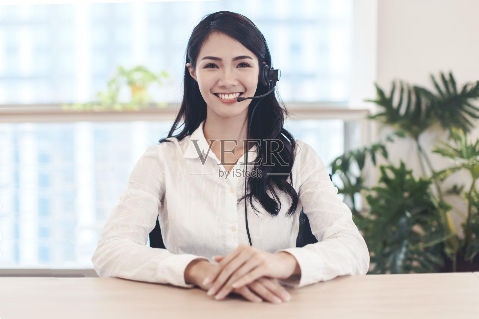 头像自信的年轻女商人看着相机和通过耳机说话。照片摄影图片