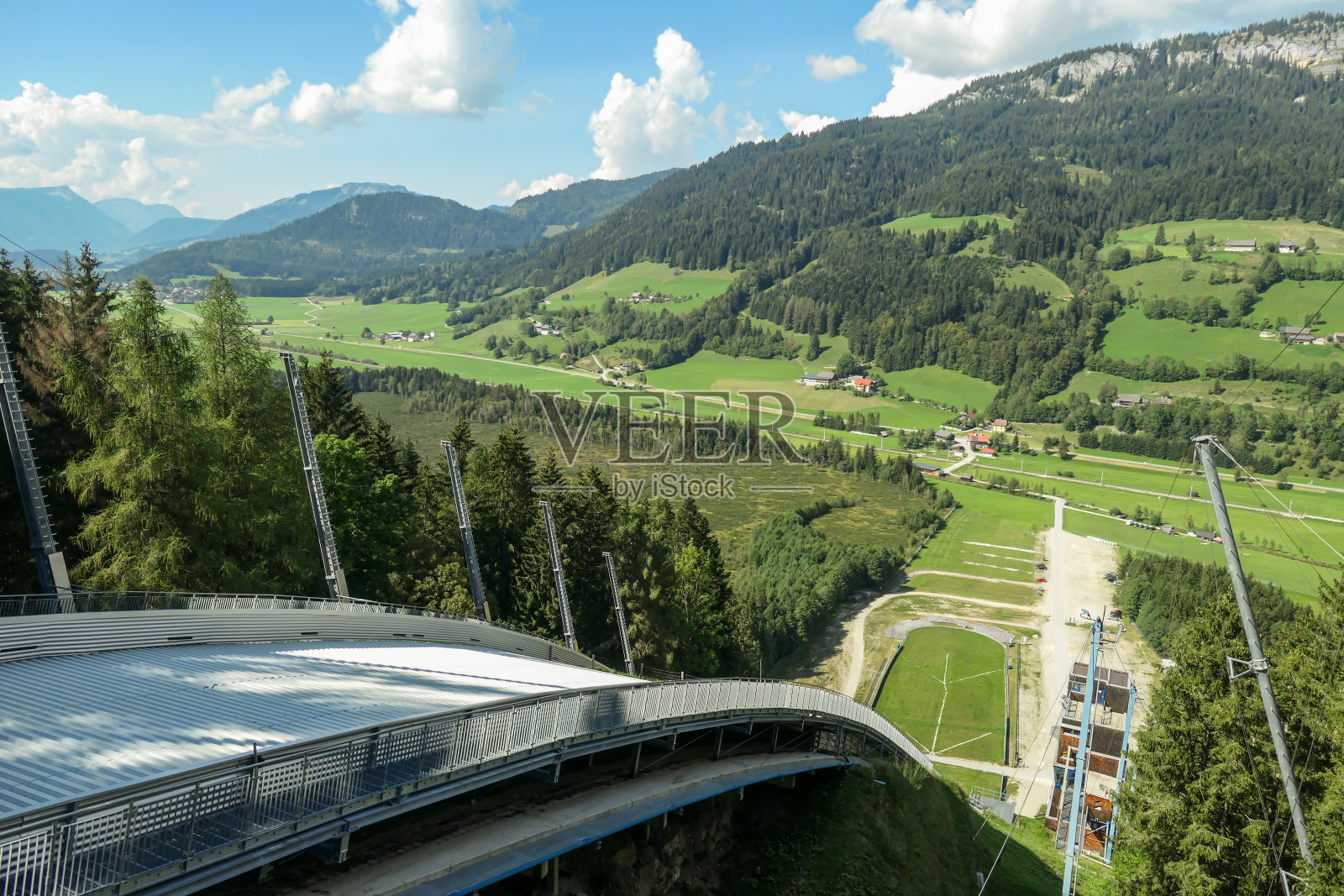 夏季,在奥地利萨尔兹卡默古特的斯蒂里安地区,从巴德密特恩多夫滑雪山顶俯瞰。跳台山周围长满了茂盛的绿色植物照片摄影图片
