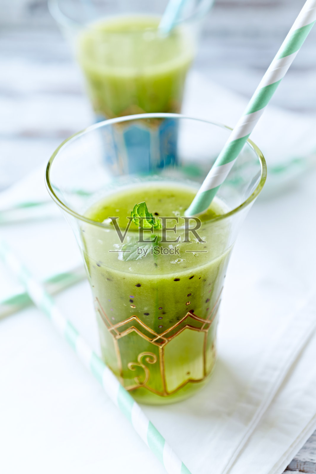 绿色的冰沙上面铺着奇异籽,明亮的木质背景。关闭了。照片摄影图片