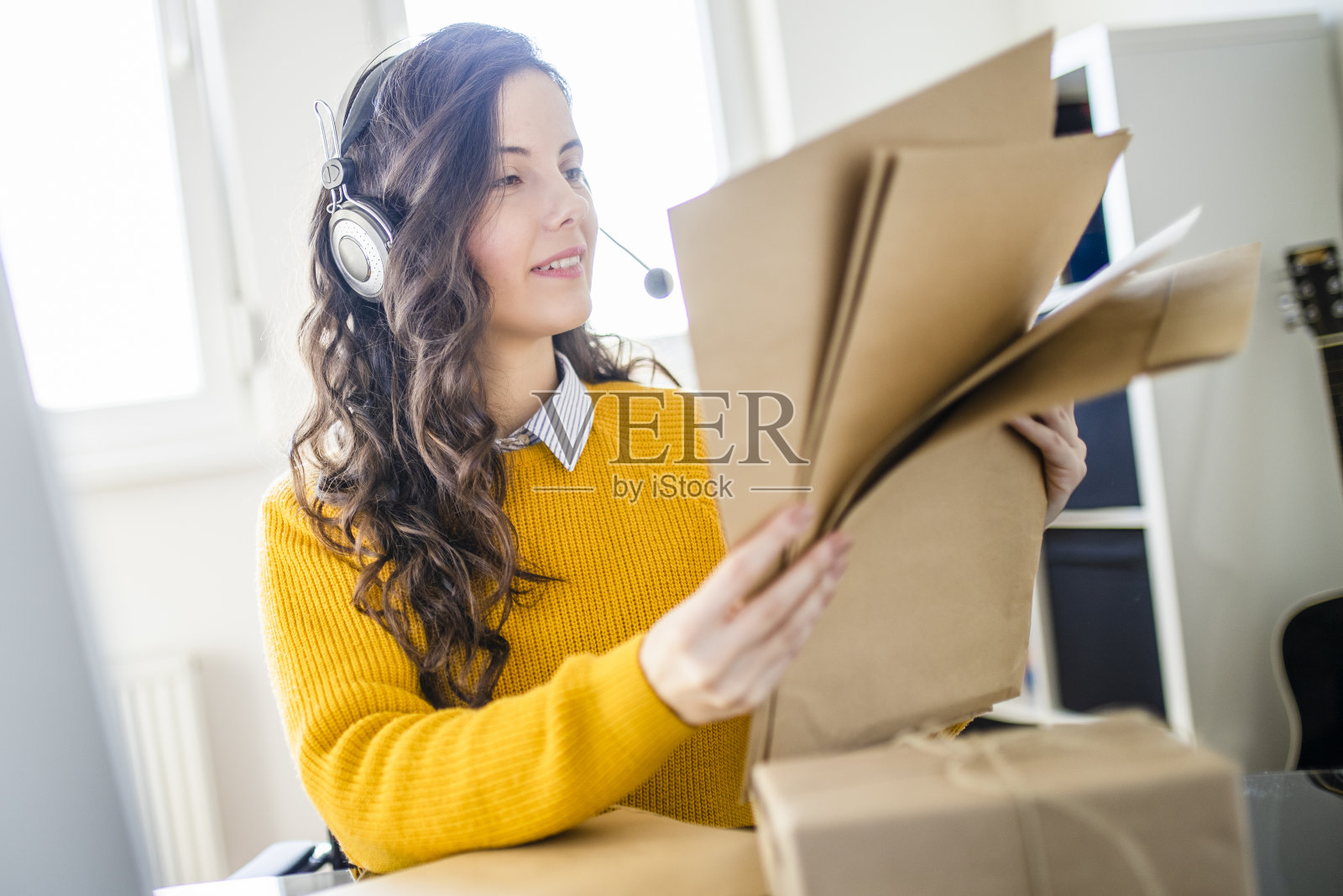 在网上商店工作的女人。她穿着休闲服,正在查看顾客的电脑地址和包装信息照片摄影图片