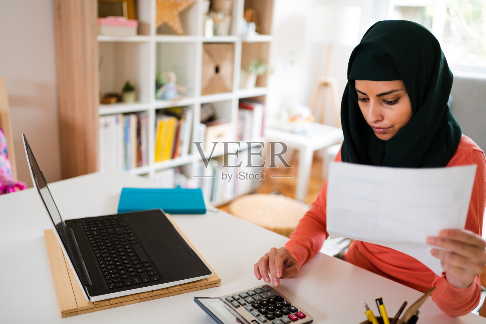 一个年轻的穆斯林妇女在网上支付账单时计算的高角度视图照片摄影图片