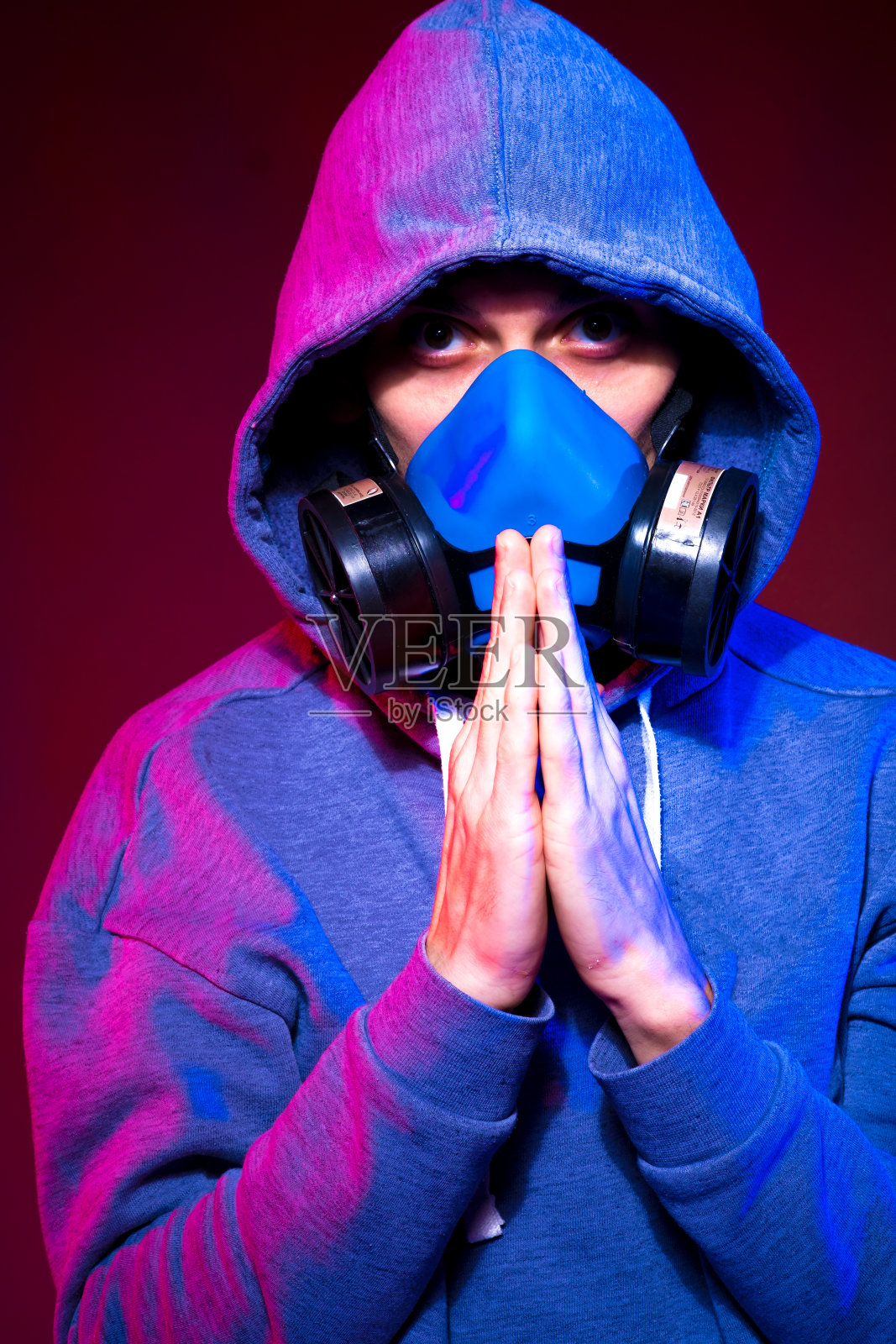 一个匿名男子的肖像,黑客戴着霓虹灯面具在黑暗的背景下。选择性地聚焦于双种族赛博朋克玩家拿着枪靠近霓虹灯照片摄影图片