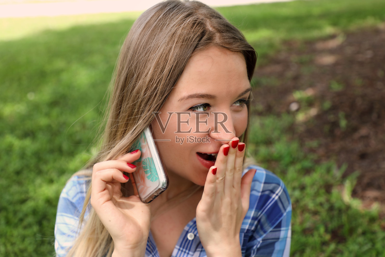 在绿色草地上使用手机的年轻女子照片摄影图片