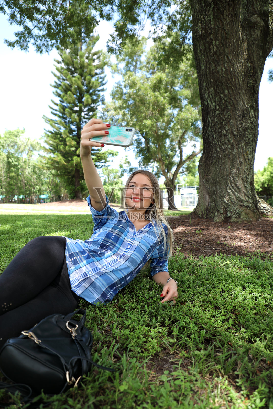 在绿色草地上使用手机的年轻女子照片摄影图片