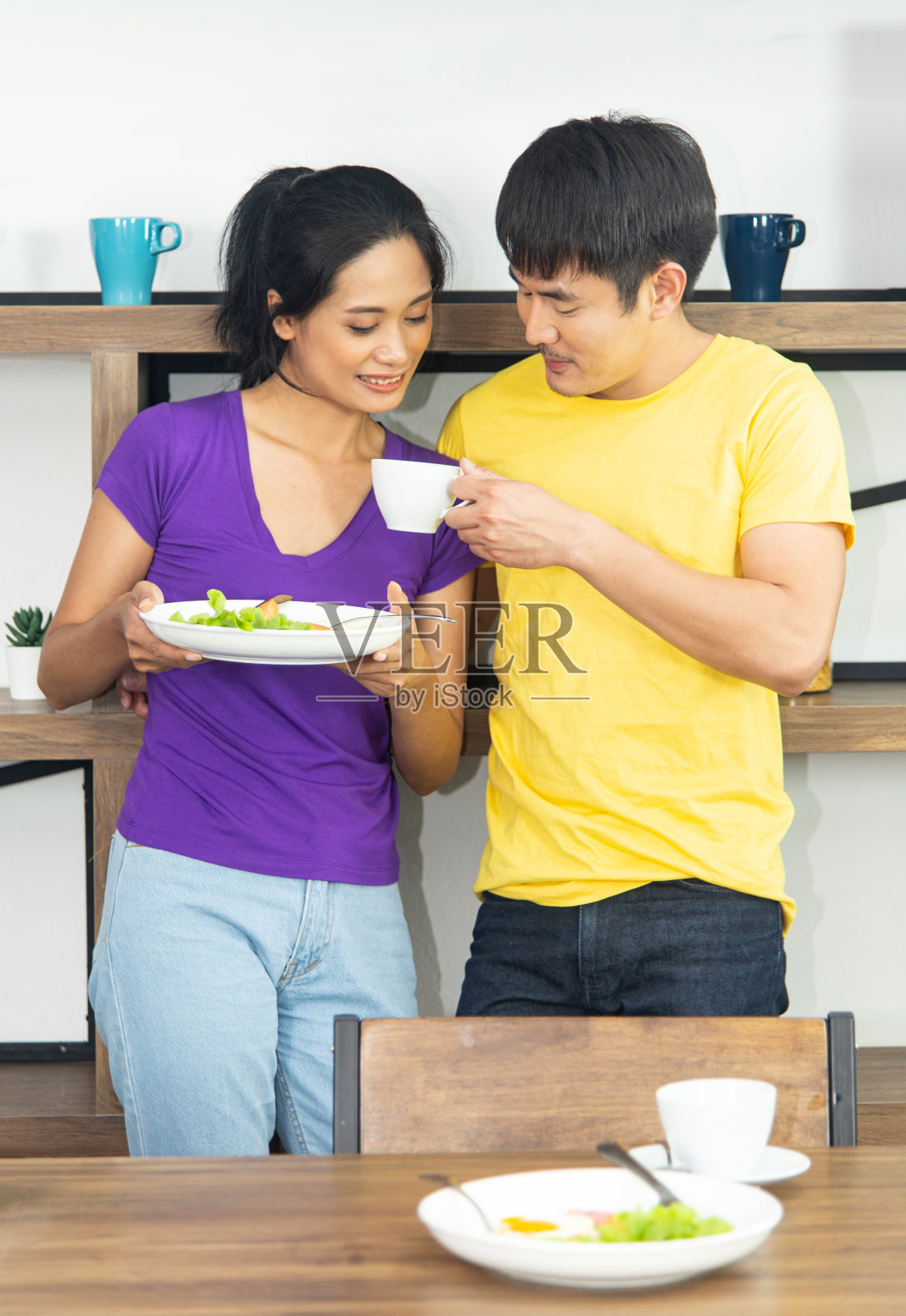 快乐有趣的家庭。亚洲可爱的夫妇,漂亮的女人和英俊的男人正在吃早餐,在厨房聊天照片摄影图片