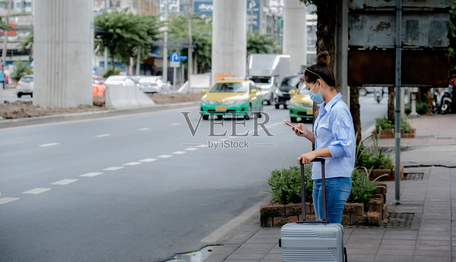 女性游客正在用智能手机上的应用程序叫车,在城里等出租车照片摄影图片
