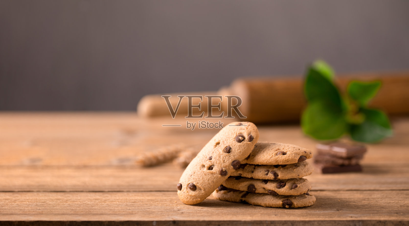 巧克力饼干堆在一起,擀面杖和绿色的树枝放在木桌上,深色的背景。横幅,复制空间。照片摄影图片