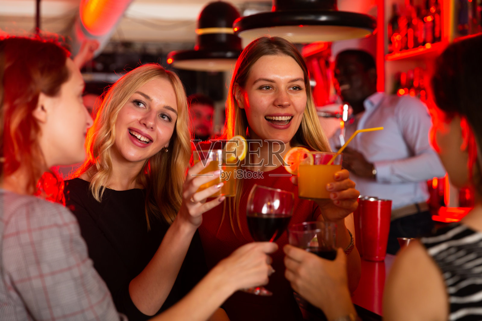 在夜总会里,朋友们捧着鸡尾酒谈笑风生照片摄影图片