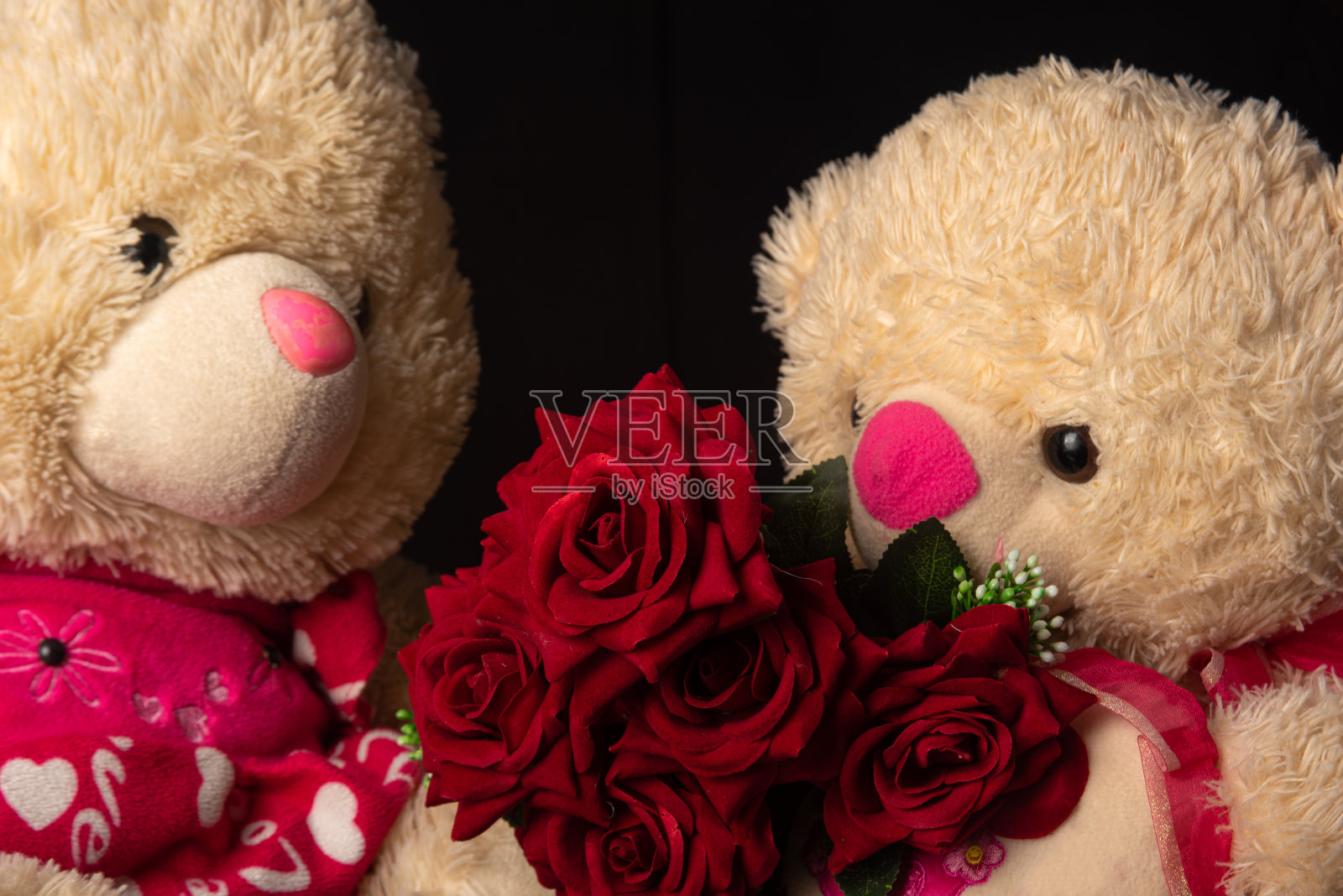 泰迪熊与红玫瑰花束的黑色背景,选择性的焦点。照片摄影图片