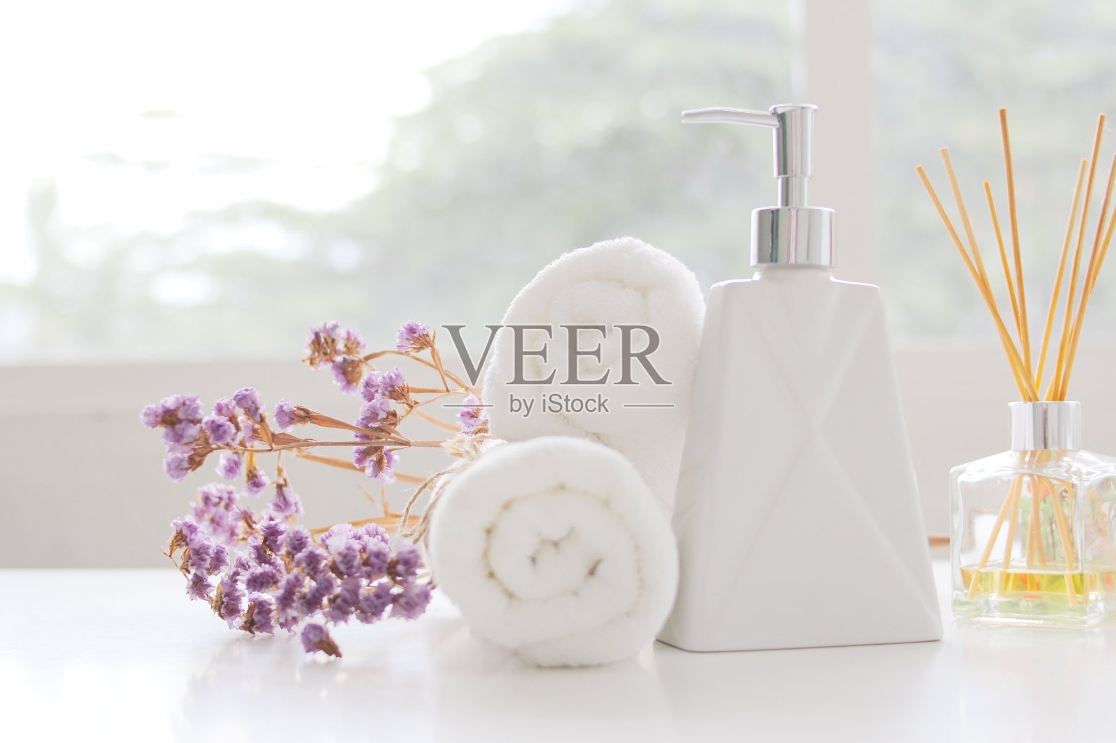 肥皂机和水疗毛巾,白毛巾卷在白色的桌子上有复印空间,毛巾工作室拍摄在白色的桌子上照片摄影图片