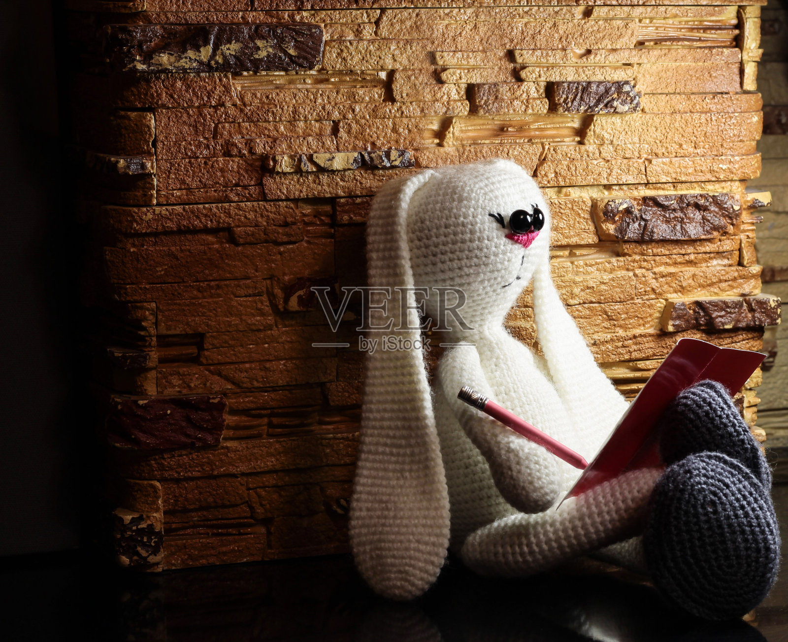 白色的兔子。白色填充玩具。用自己的双手编织玩具。兔子在读一本书。商业兔盘腿而坐。照片摄影图片